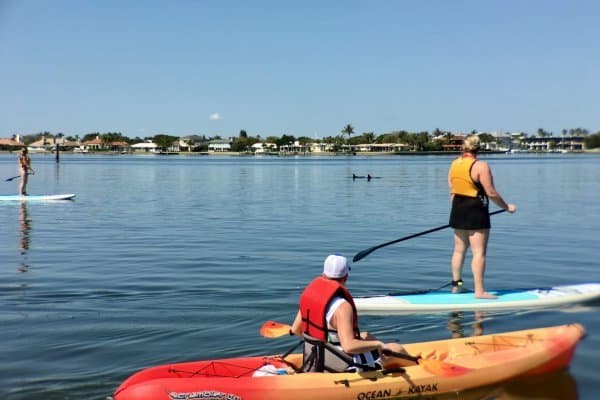 Young man kayaking next to tour guide on paddle board