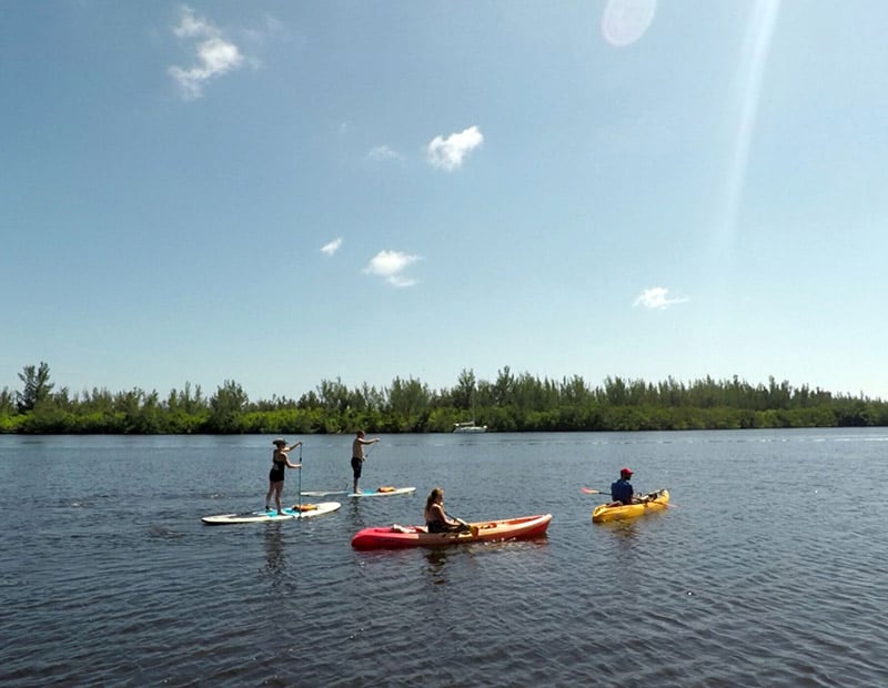 Two people paddle boarding and two people kayaking in the Indian River Lagoon
