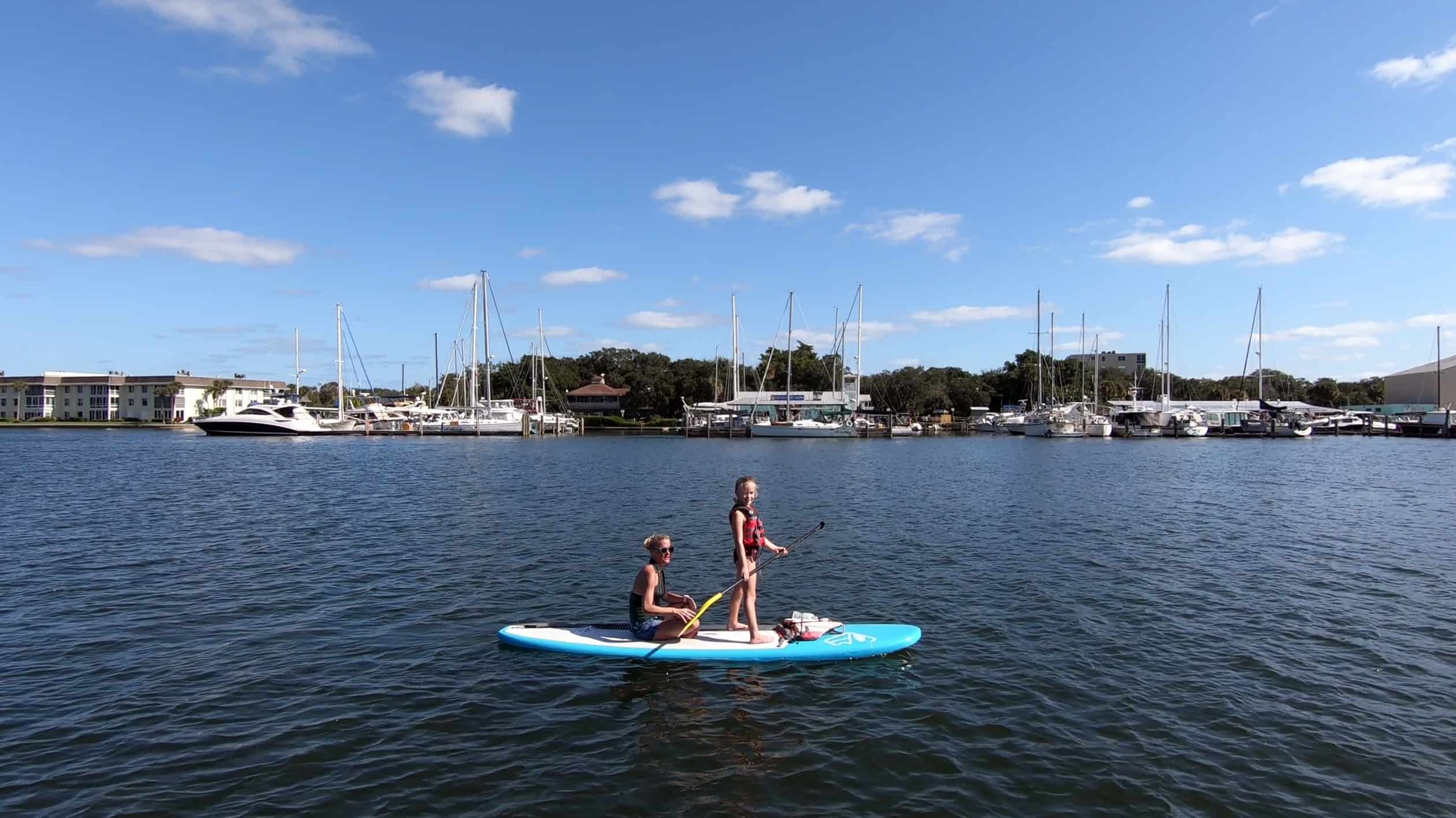 Mother sitting and daughter standing on paddle board in Vero Beach