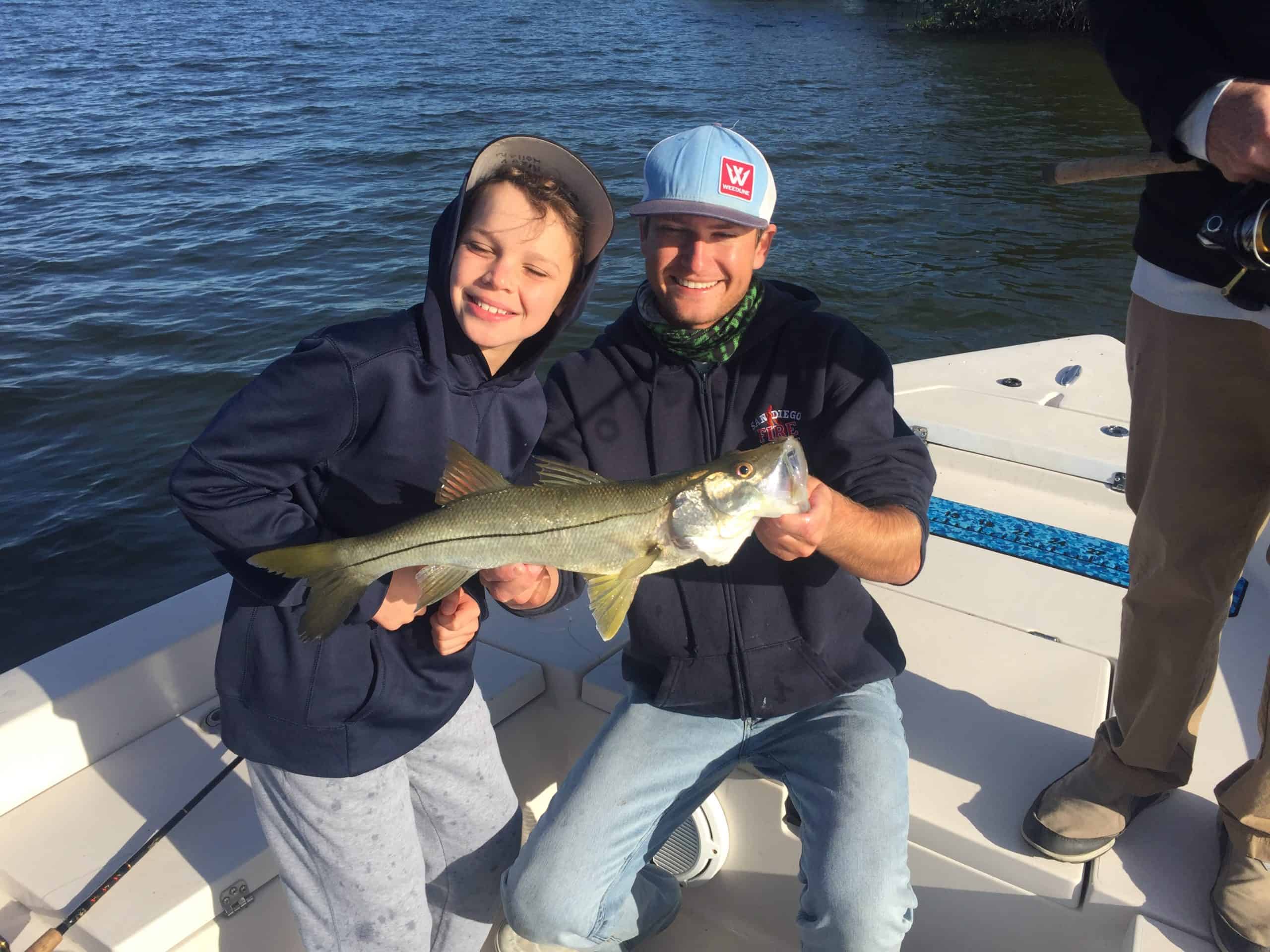 Fishing charter captain Matt Reynolds holding fish next to young boy